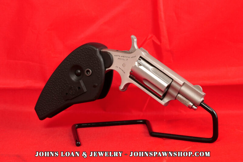 North American Arms .22 Magnum mini-revolver from John's Loan & Jewelry, showcasing its stainless steel frame, textured black holster grip, and single-action mechanism, presented on a black display stand.