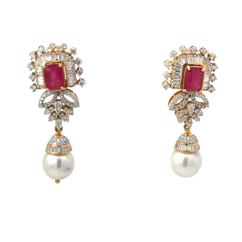 Pair of John's Loan & Jewelry 18K yellow gold earrings featuring a central faceted ruby, surrounding diamond halo, and a lustrous pearl drop on a white table.