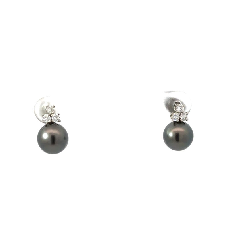 Two 14kt white gold earrings from John's Loan & Jewelry featuring round, black pearls with a trio of prong-set diamonds above, displayed on a white table.
