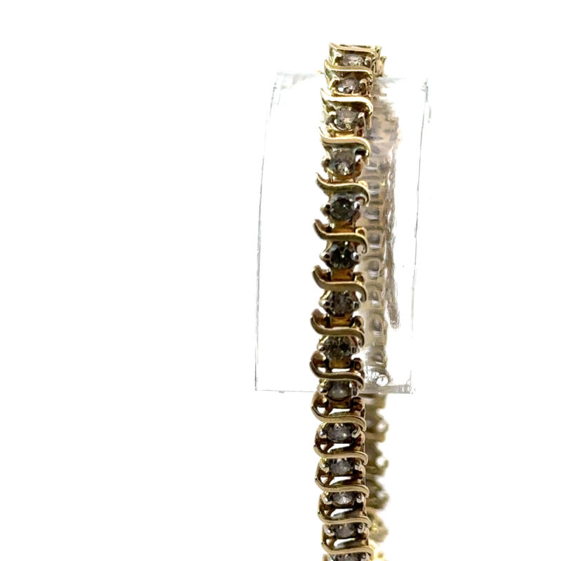 Close-up image of a John's Loan & Jewelry 10k yellow gold tennis bracelet featuring individually set, natural diamonds, displayed vertically against a white table surface.
