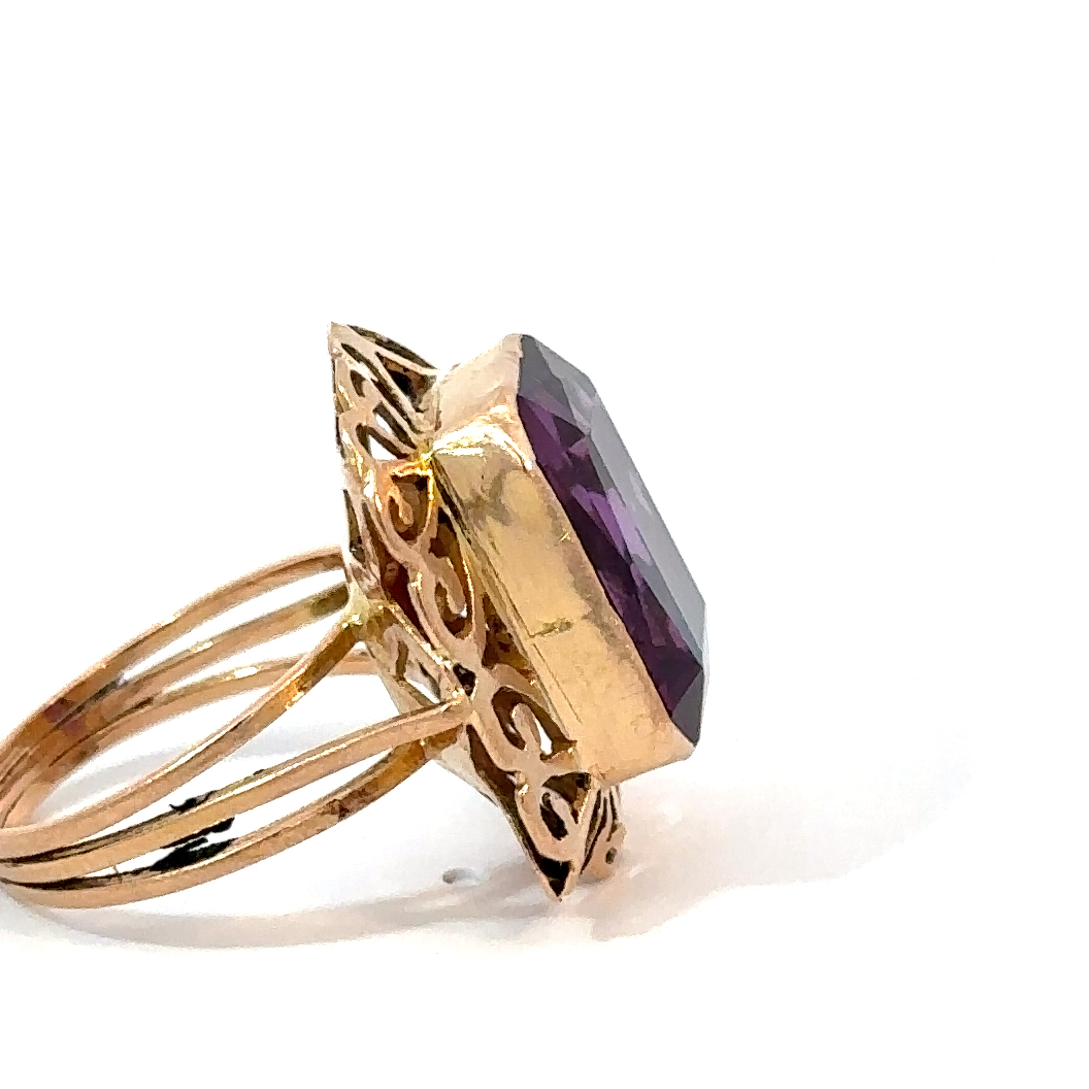 Side-profile view of an 18k yellow gold amethyst ring from John's Loan & Jewelry, showcasing the stone's depth and the ring's multi-band design and ornate gold setting.