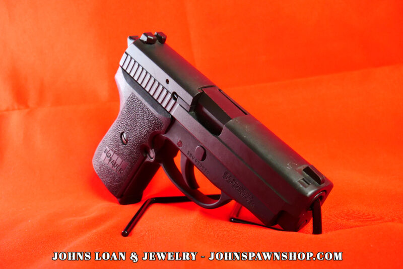 Side-profile image of the German-made Sig Sauer P239 semi-auto pistol, in 9mm, resting on a display stand from John's Loan & Jewelry, a Las Vegas pawn shop firearm.