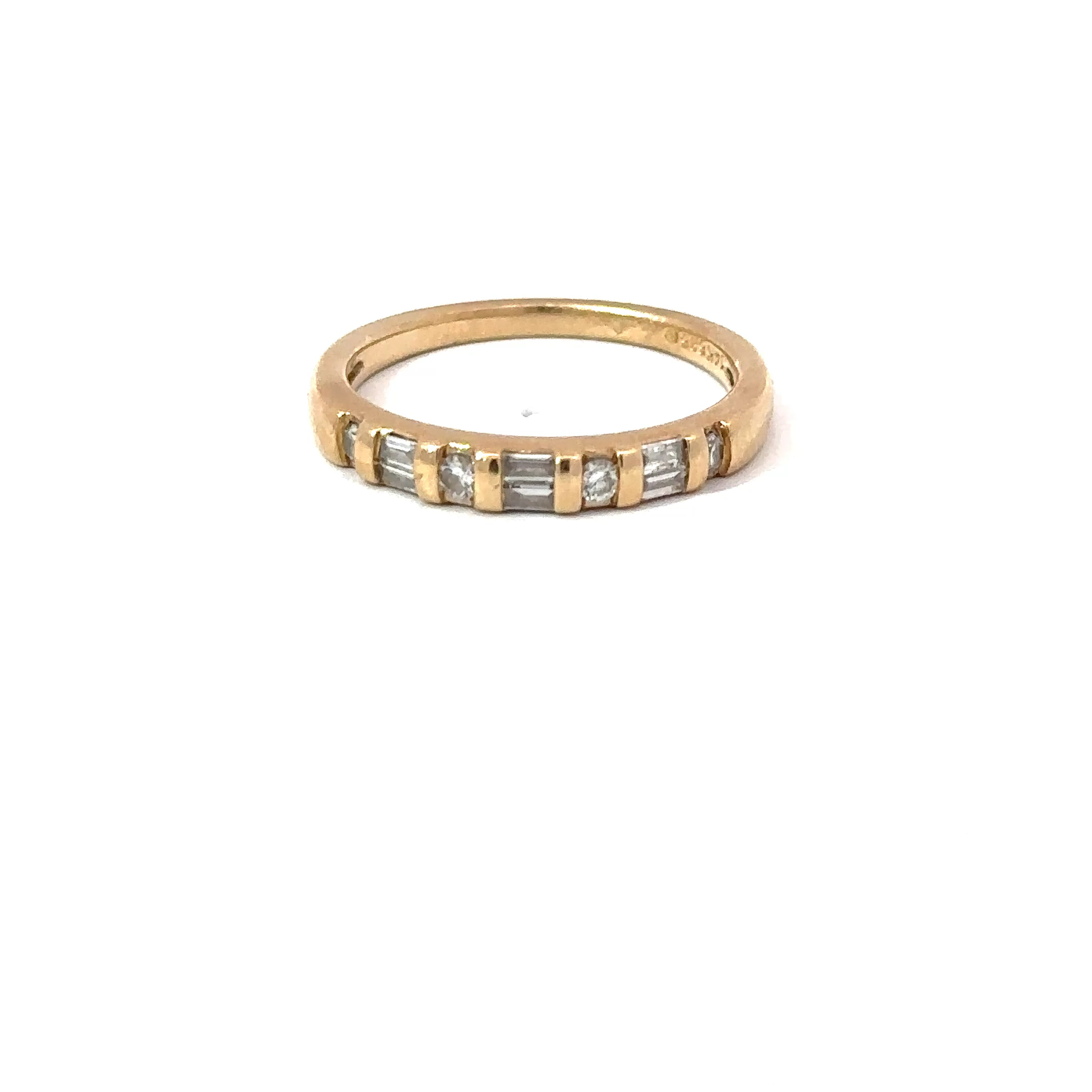 Angled view of a John's Loan & Jewelry 14kt yellow gold stacker band ring featuring baguette-cut diamonds set horizontally across the top, displayed on a white table surface.