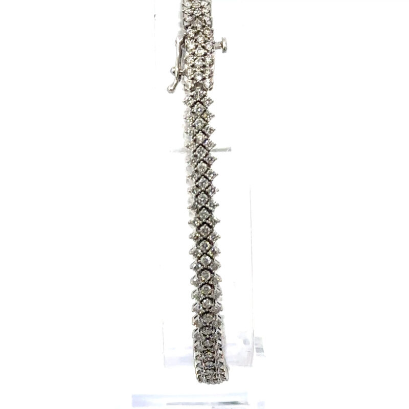 Close-up image of a 10K white gold bracelet from John's Loan & Jewelry, featuring three parallel rows of prong-set diamonds against a stark white background.